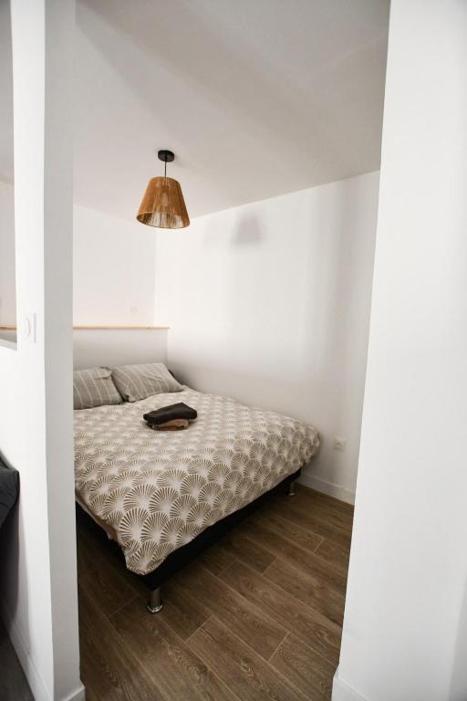 a bed in a white room with a lamp at Le Petit Cocon in Château-Chinon