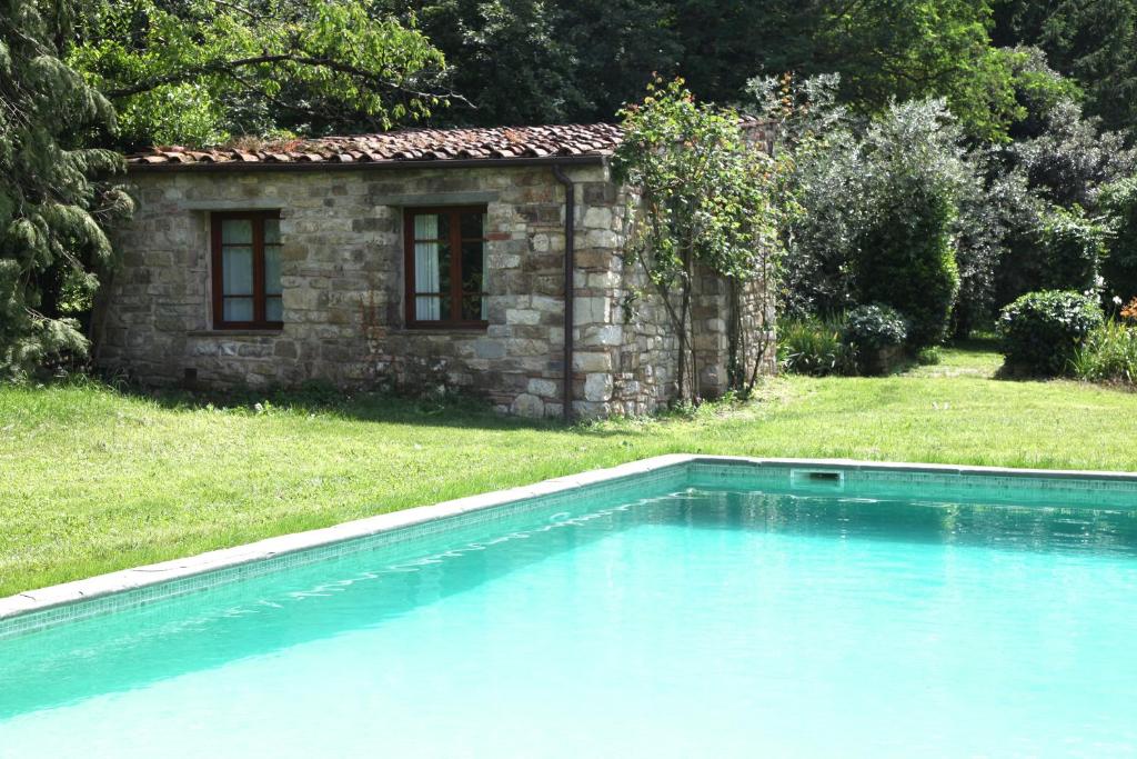 a swimming pool in front of a stone house at Villa Organi in Vaiano
