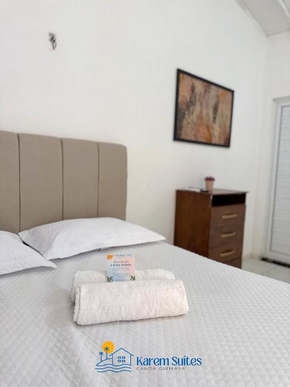 a bed with two towels sitting on top of it at Karem Suítes in Aracati