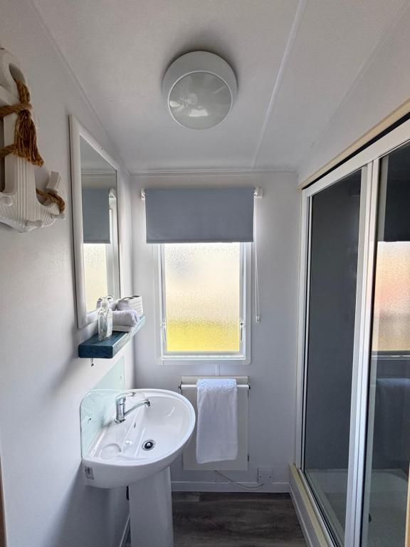 ein weißes Badezimmer mit Waschbecken und Fenster in der Unterkunft Family-Friendly 3-Bed Caravan Recently Renovated on Seven Bays Holiday Park, Padstow in Saint Merryn