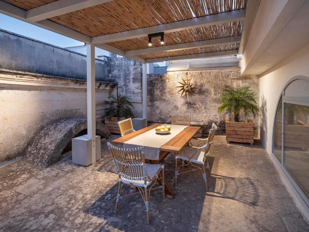 Un patio con mesa y sillas y un muro de piedra. en Palazzo Alchimia, en Fasano