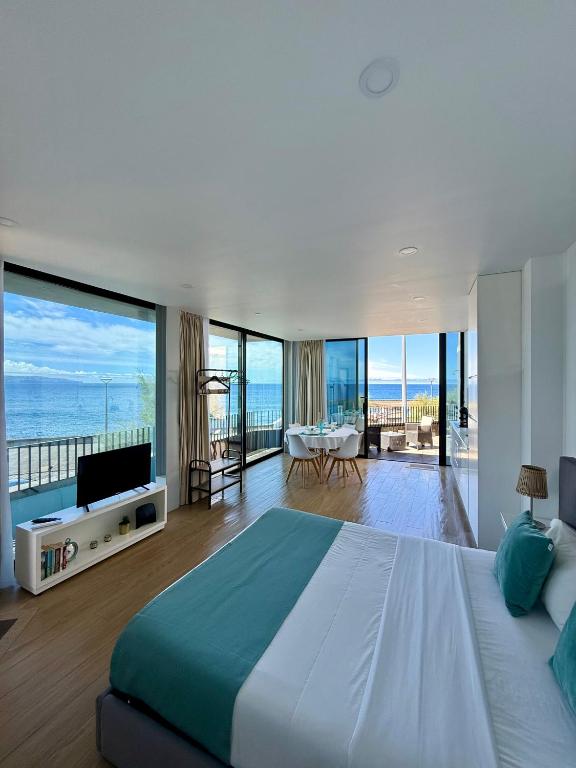 a bedroom with a large bed and a view of the ocean at Casa do Horizonte in Ribeira Grande