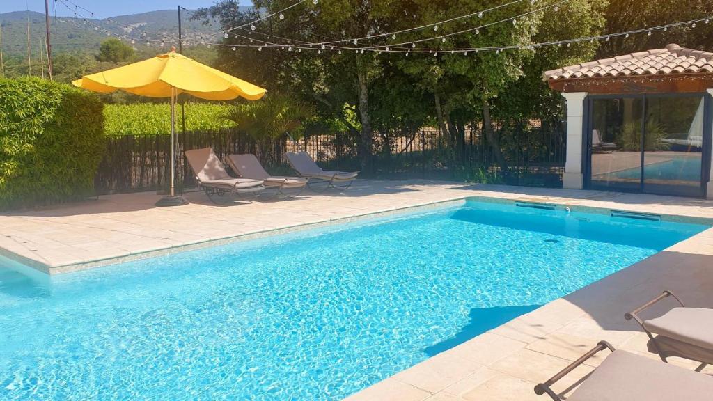 a swimming pool with an umbrella and chairs and an umbrella at Les Tournillayres in Bédoin