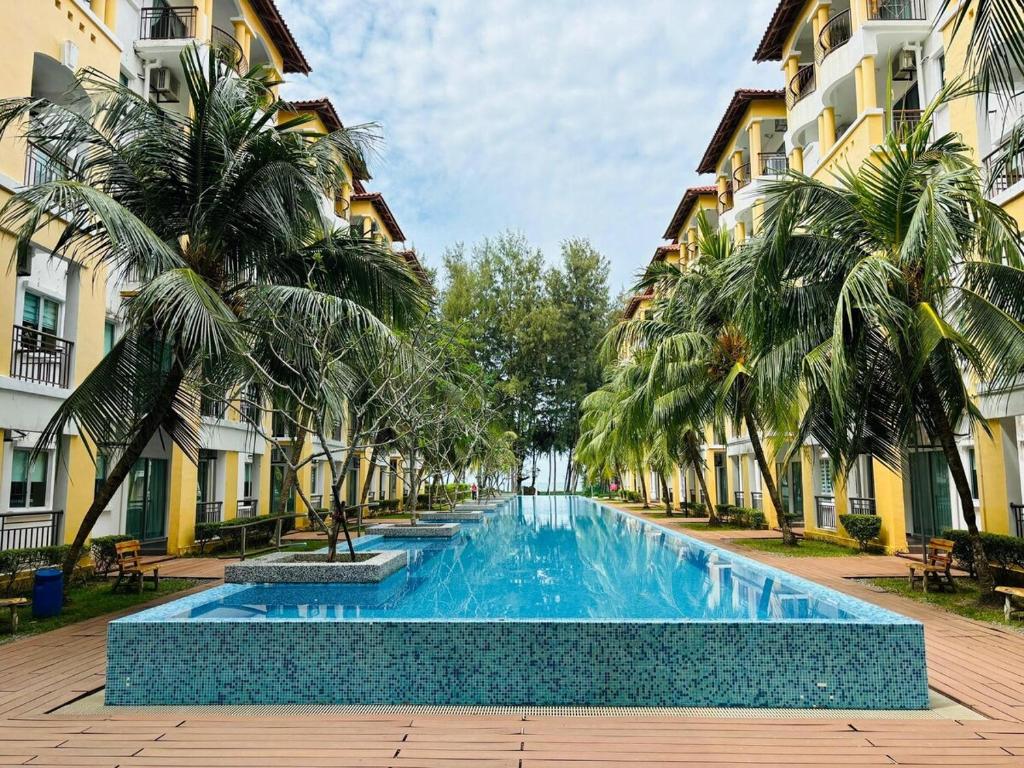 a swimming pool in a courtyard with palm trees and buildings at Desaru Beach Luxury Suites Pool View 3Pax E1 in Bandar Penawar