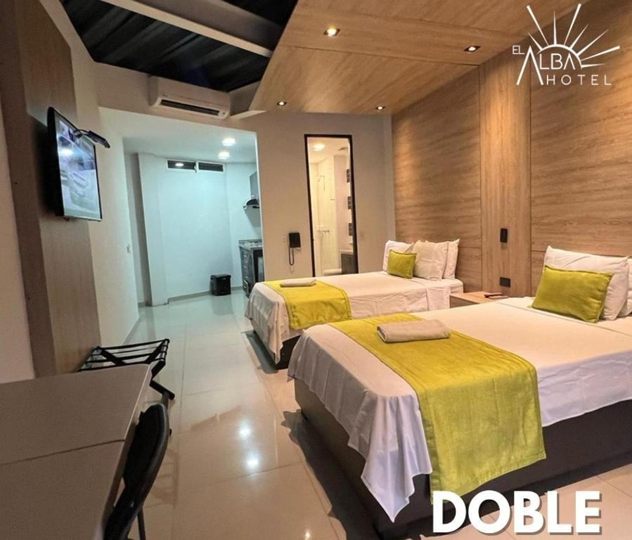 a hotel room with two beds with yellow sheets at Hotel El Alba in Cali