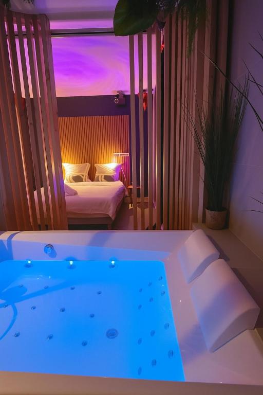 a room with a tub and a bedroom with two beds at Séjour Insolite ,SPA SAUNA parking gratuit in Troyes