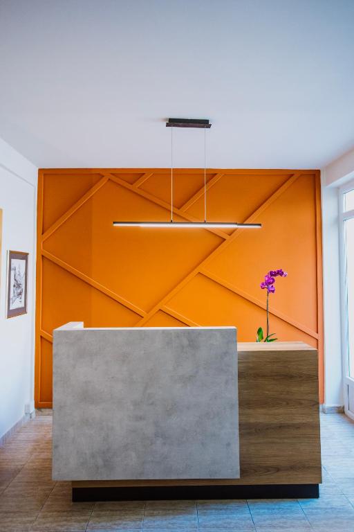 a lobby with a reception desk with an orange wall at Artelo - Inspired Stay in Bitola