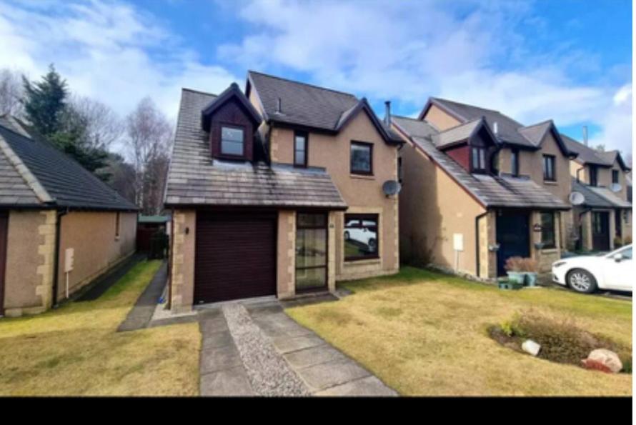 a large house with a garage in a yard at 6 Carn Dearg House in Aviemore