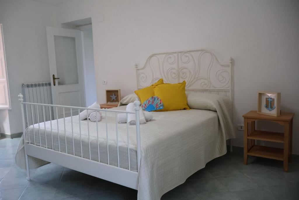 a bedroom with a white bed with yellow pillows at Casa Flaùti Sorrento in Piano di Sorrento