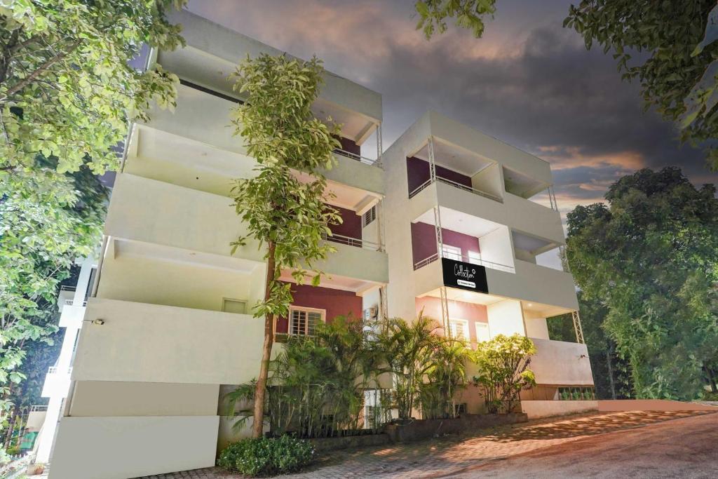 a white building with trees in front of it at Collection O Hebbal Mysore in Mysore