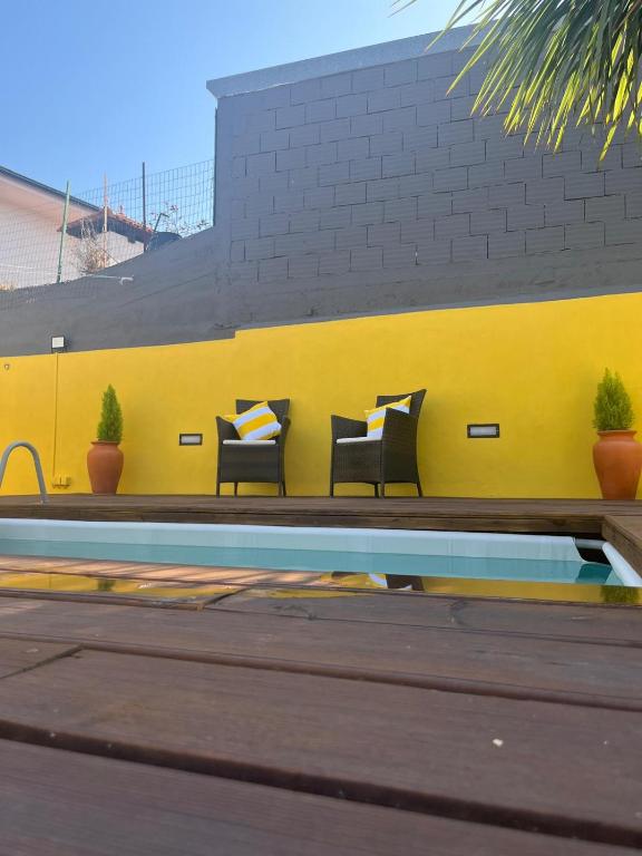 a bench with pillows sitting next to a yellow wall at Memórias in Nogueira da Regedoura