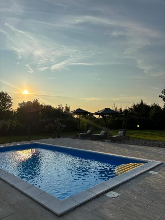 a swimming pool with a sunset in the background at Villa Stone House in Debeljaci
