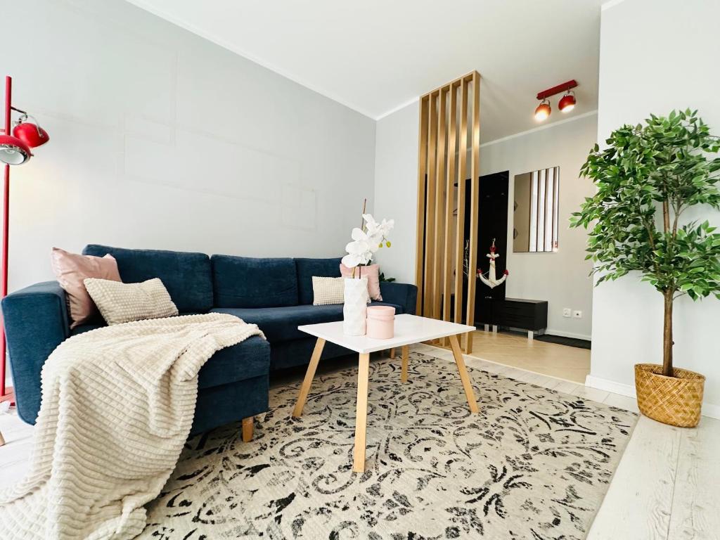 a living room with a blue couch and a table at Apartament Kryształowy - Kołobrzeg in Kołobrzeg