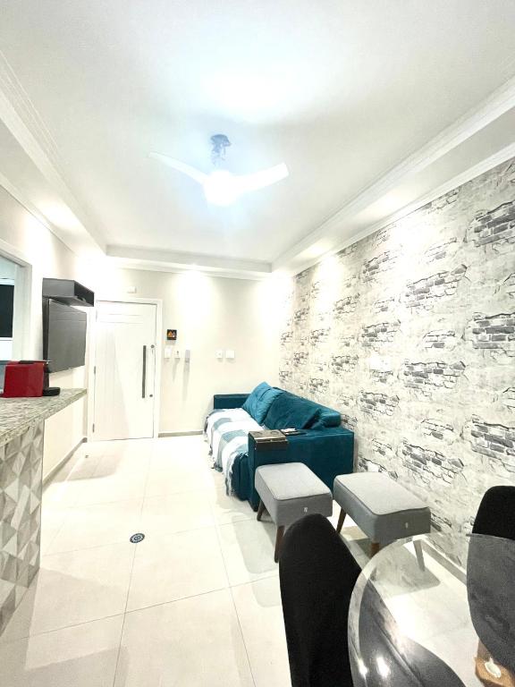 a living room with a blue couch and a stone wall at Santos Prime Stay in Santos