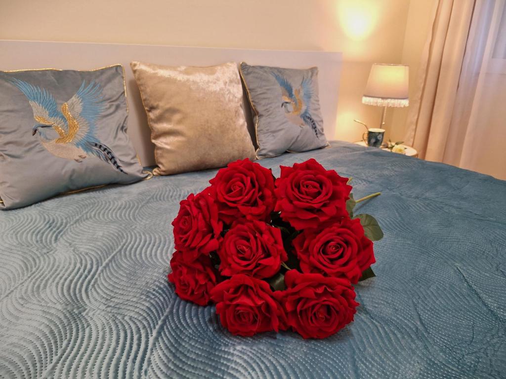 a bouquet of red roses sitting on a bed at Albina apartman in Eger