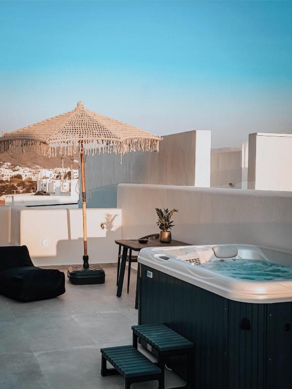 a room with a hot tub and a table and an umbrella at Nonna's Suites in Naxos Chora