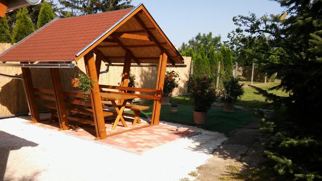 a wooden gazebo with a bench in a yard at Gerendás Vendégház in Sótony