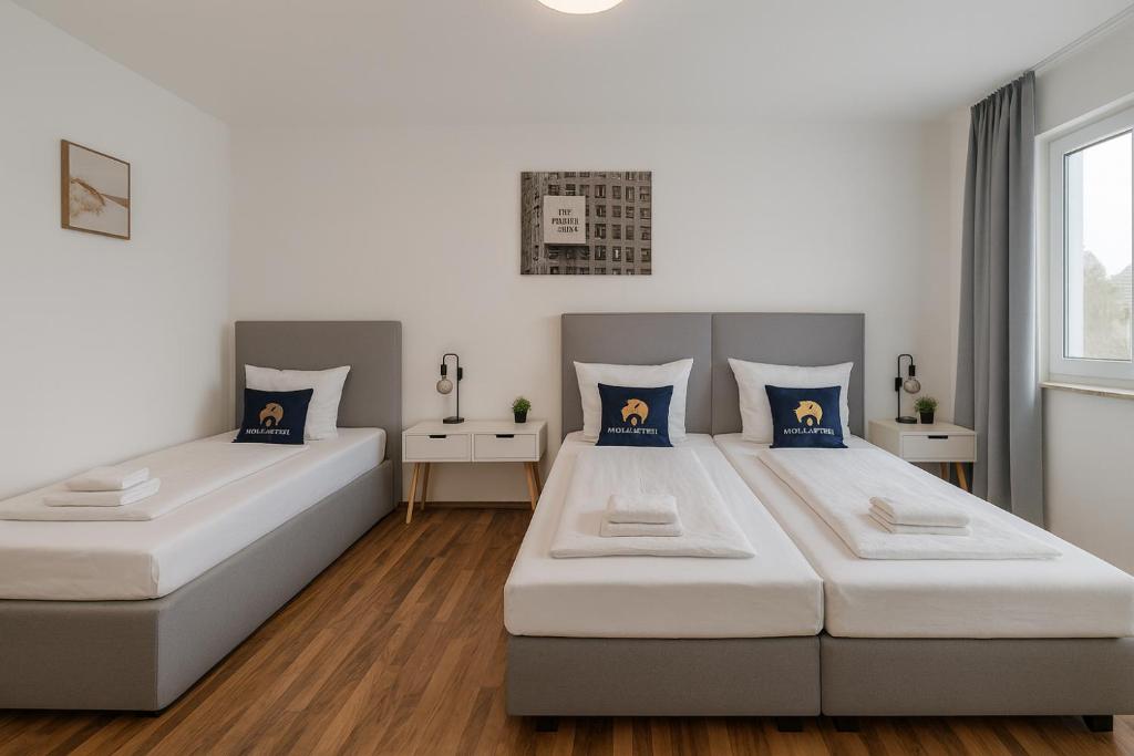 two beds in a room with white and blue pillows at SMS-Homes I Auszeit in Heilbronn in Heilbronn