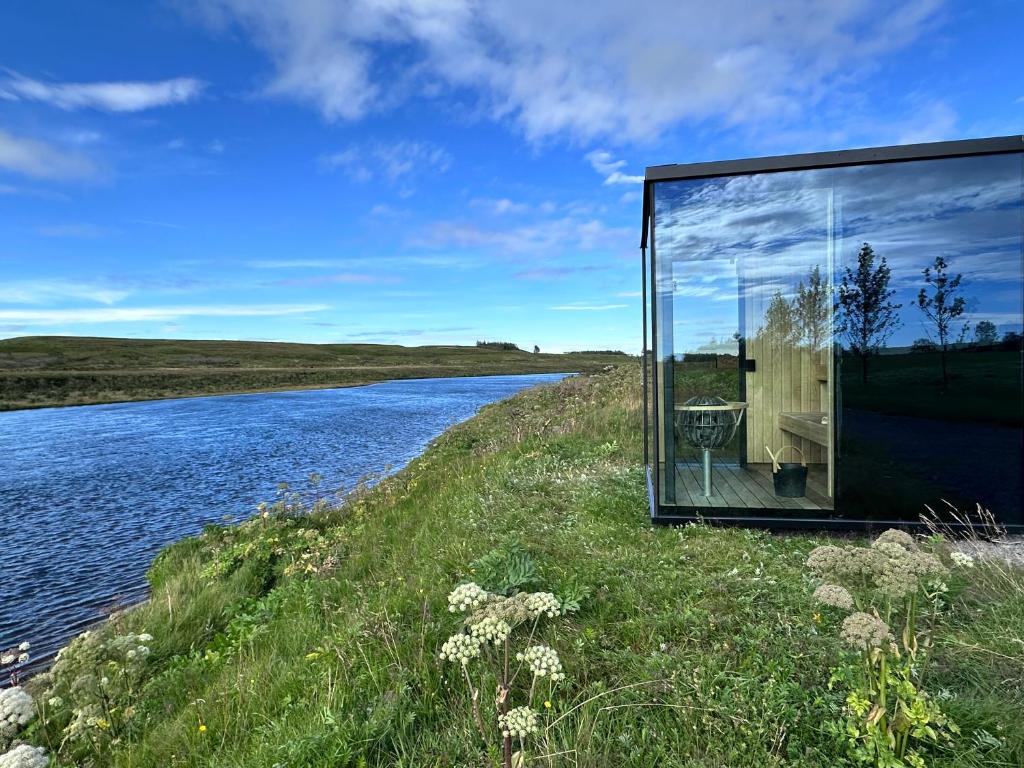 una casa de cristal a orillas de un río en Nest Retreat Iceland, en Hella
