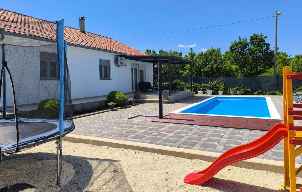 a playground with a red slide next to a swimming pool at Three-Bedroom Holiday Home In Vinjani Gornji in Aračići