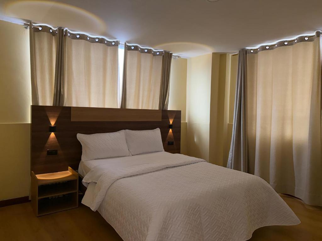 Un dormitorio con una cama con una colcha blanca. en Hotel Suyusama, en Ipiales