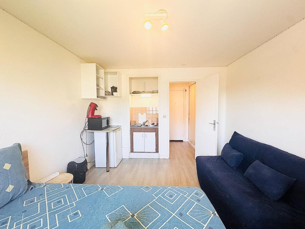 Una sala de estar con un sofá azul y una cocina. en Studio pour 2 près de la gare, en Melun