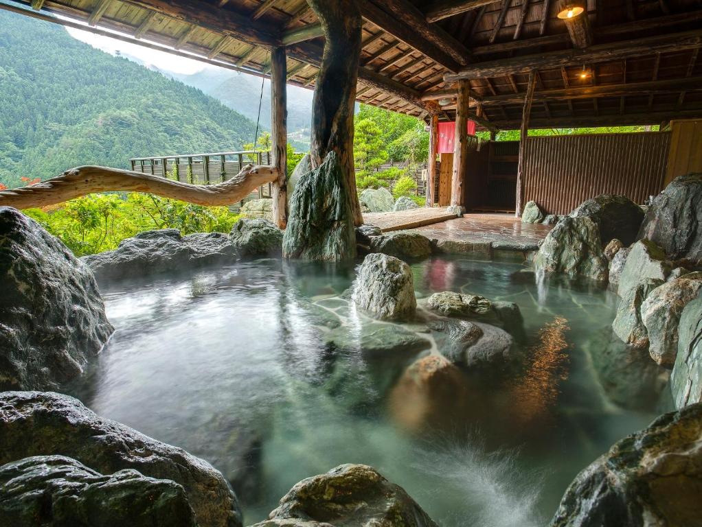 a hot spring in a building with rocks and water at Hotel Kazurabashi in Miyoshi