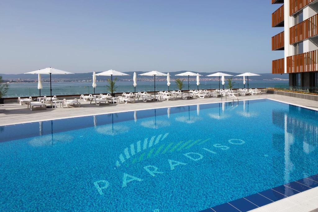 uma piscina com cadeiras e guarda-sóis num hotel em Aparthotel Paradiso em Nessebar