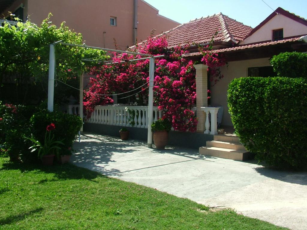 una casa con flores rosas y una valla blanca en Spiridoula apartments en Agios Stefanos