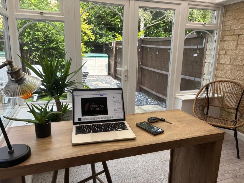 a laptop computer sitting on a wooden table in a room at Redwing Retreat - Luxury 2 Bed - Quiet Home with Garden - Walk to Bicester Village - Driveway Parking - Sleeps up to 6 in Bicester