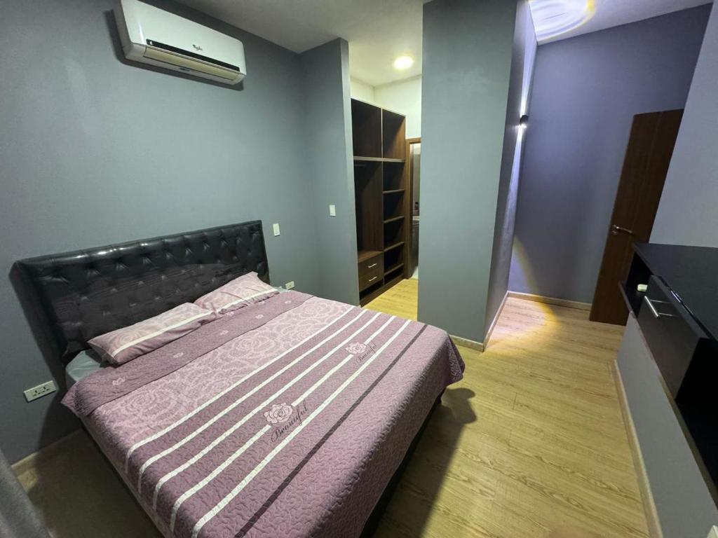 una camera con un letto con una parete viola di Departamento amplio en el corazón de Santa Cruz a Santa Cruz de la Sierra