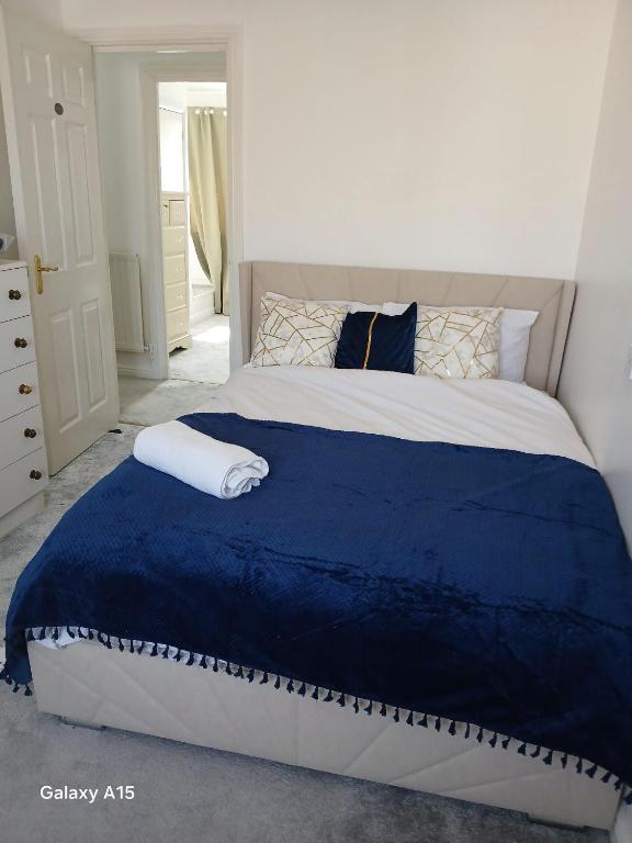 a bedroom with a large bed with a blue blanket at Luton Homes in Luton