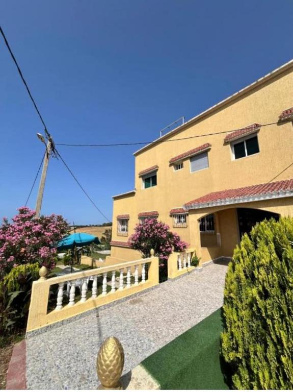 a building with a fence next to a yard at Villa Diki beach in Ksar es Sghir