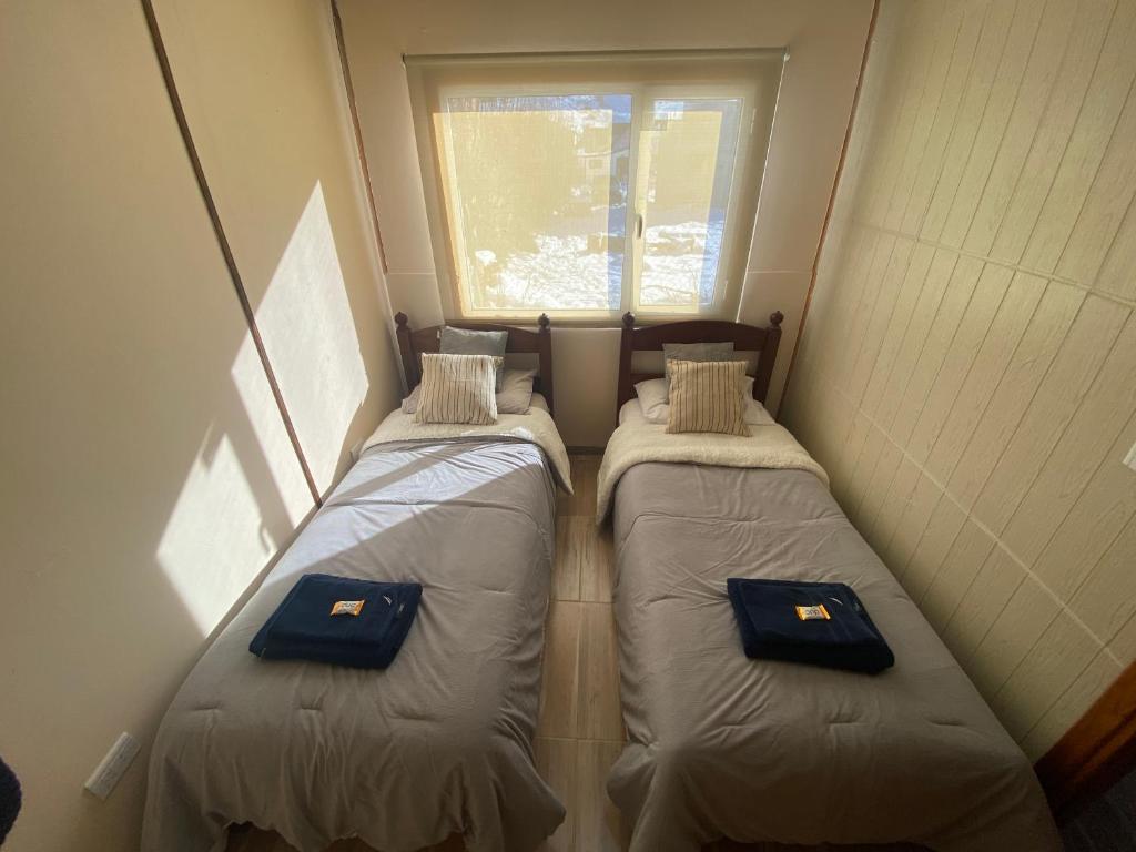 deux lits dans une petite pièce avec une fenêtre dans l'établissement Samsara, à El Chalten