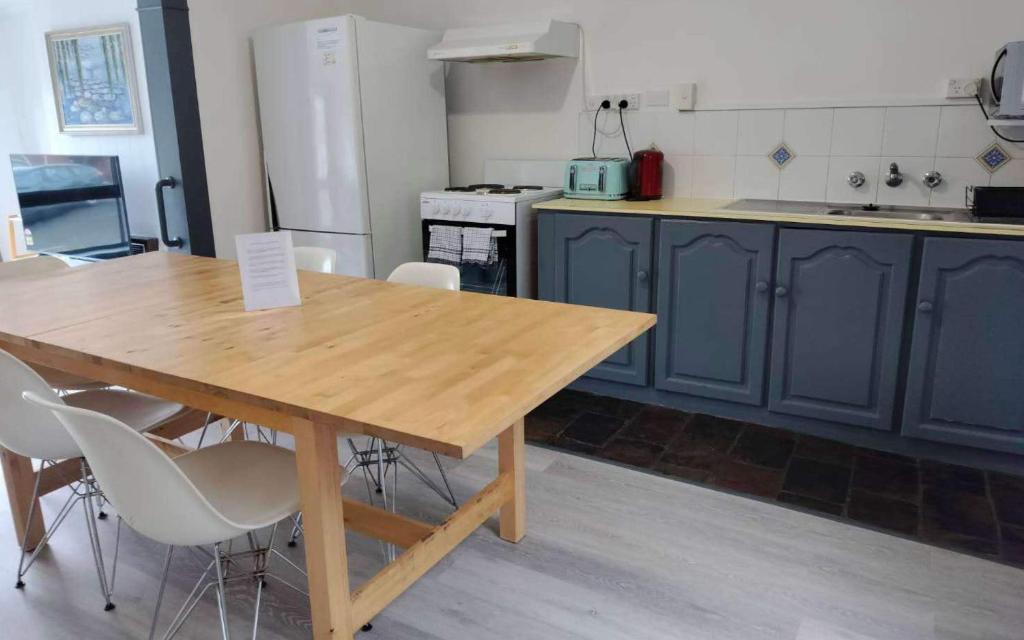 霍巴特Wellesley Mountain House near City的厨房配有木桌和白色椅子