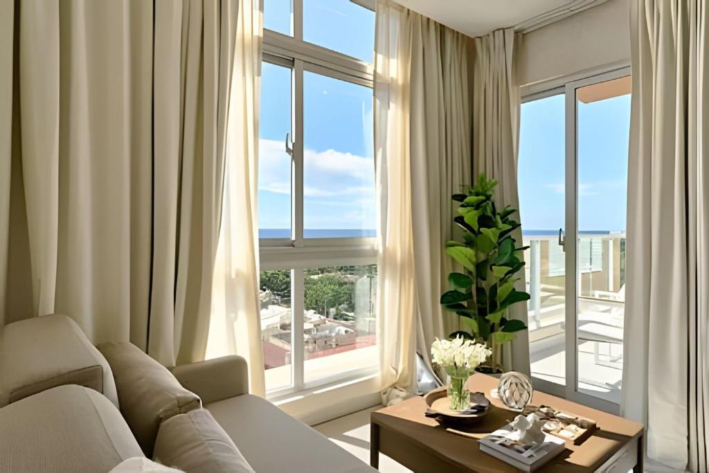 a living room with a couch and a large window at Costal View Apt. Walkable To Beach & Restaurants in Juan Dolio