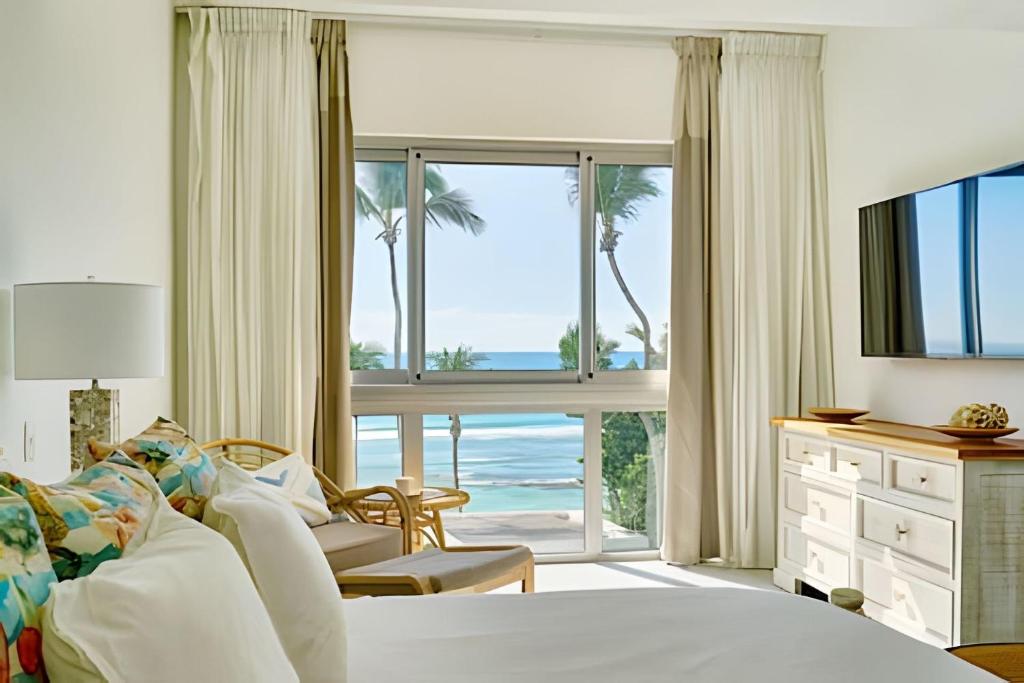 a bedroom with a bed and a view of the ocean at Caribbean Sunscape Beachfront Apartment in La Puntica de Juan Dolio