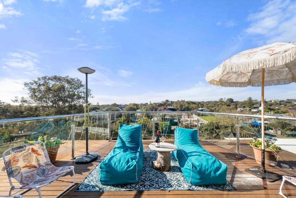 a deck with blue pillows and a table and an umbrella at Epic Rye Penthouse with Bubble Dome & Amazing Views! in Rye