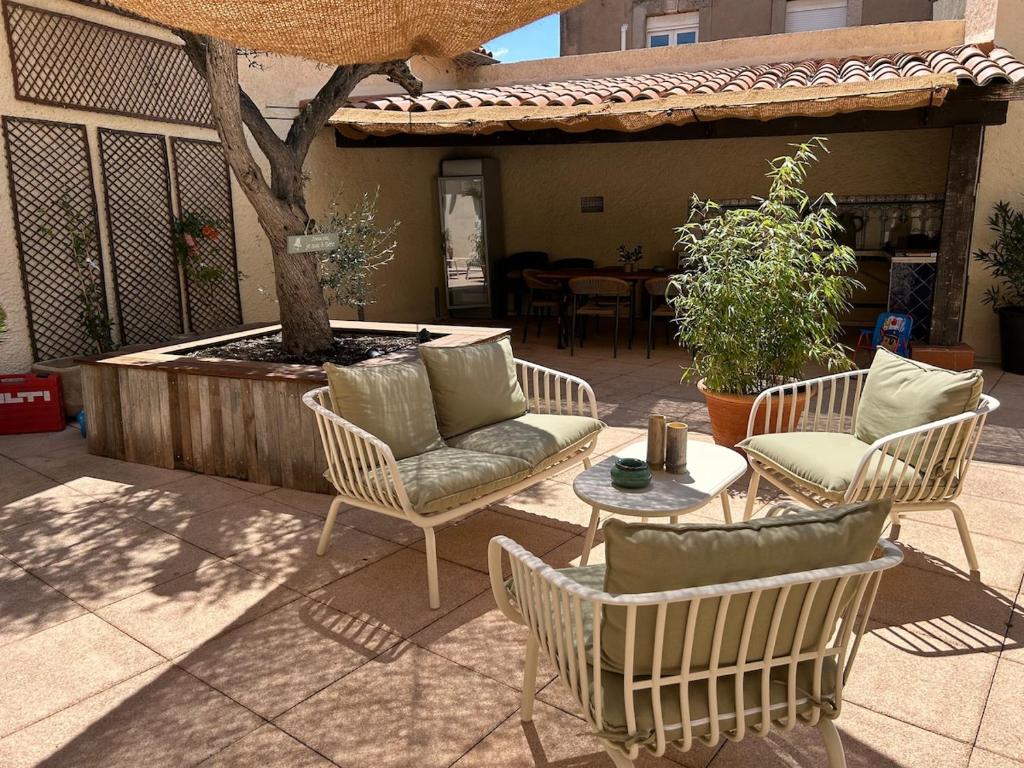 un patio con 2 sedie, un tavolo e un albero di Les Reflets dAngele Terrasse XXL a Sete a Sète