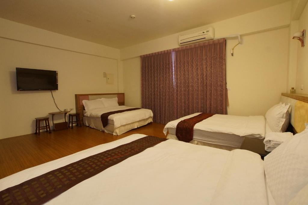 a hotel room with three beds and a flat screen tv at Bang Qiaonuo - Peng&#39;s family in Taitung City