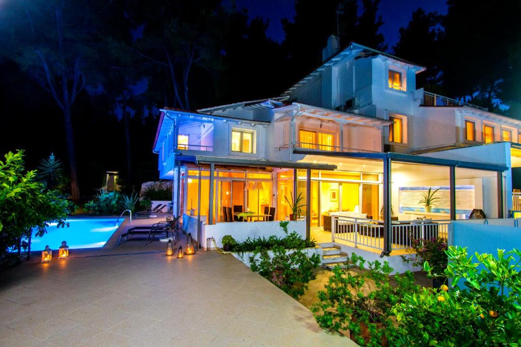 a large white house with a swimming pool at night at Muses Villas Resort in Sani Beach