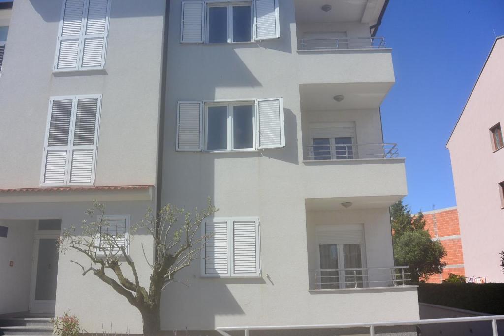 un edificio con ventanas blancas y un árbol delante en Apartments Residence L'Ulivo, en Rovinj
