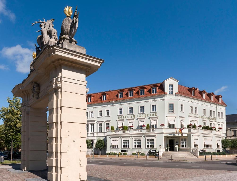 uma estátua em frente a um grande edifício branco em Hotel Am Jägertor em Potsdam