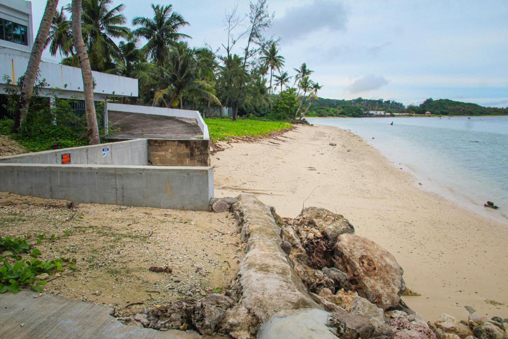 a sandy beach with a building and the water at Playa Del Pedro Beach House in Guam