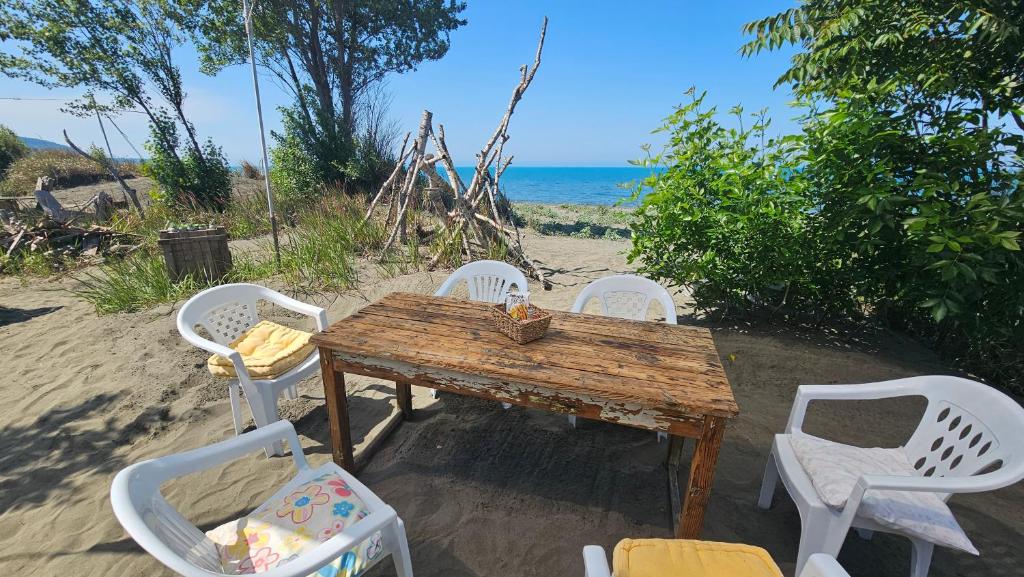 a wooden table with four white chairs and the beach at Beachfront Caravans in Chernomorets