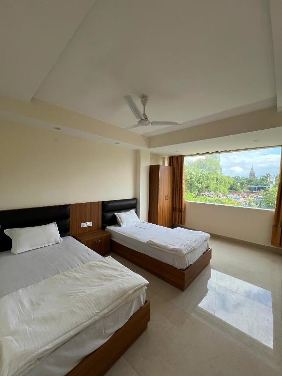 two beds in a room with a large window at The ZEN INN , Pure veg hotel in Bodhgaya in Bodh Gaya