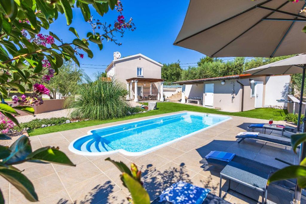 un patio trasero con piscina y sombrilla en Villa Frana, en Krk