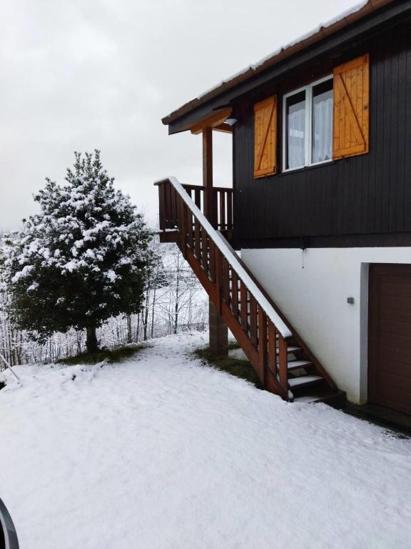 a house with a snow covered porch and a tree at Chalet le Petit Coeur in Xonrupt-Longemer