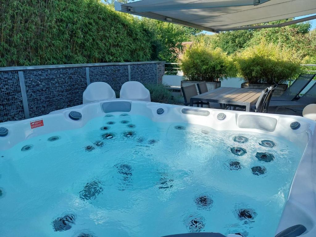 a hot tub in a backyard with a table and chairs at Gite Spa les Estinnes in Estinnes-au-Mont
