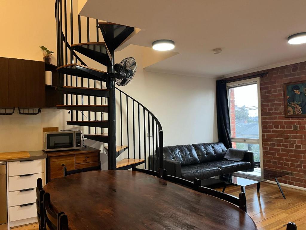a living room with a table and a spiral staircase at Brickworks Heritage Loft in Melbourne